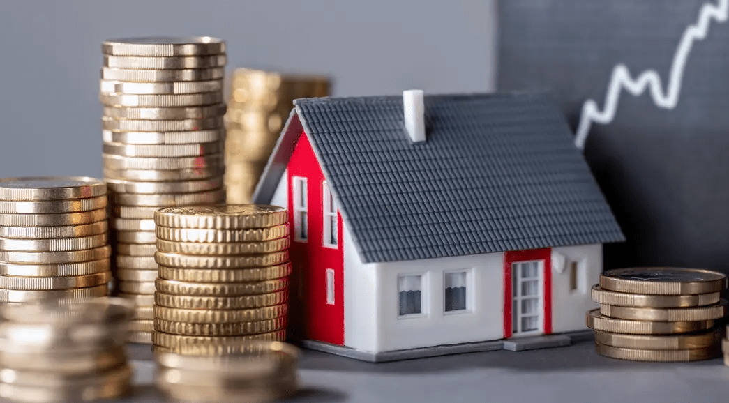 Model house surrounded by stacked coins