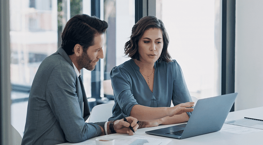 Two agents in an office reviewing information on a laptop
