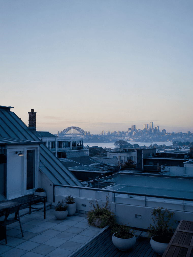 Sydney rooftop terrace at dusk with the Harbour Bridge and CBD skyline in the distance